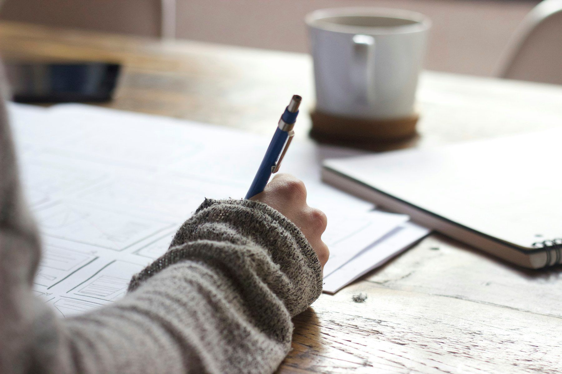 A person writing figures on paperwork at a desk