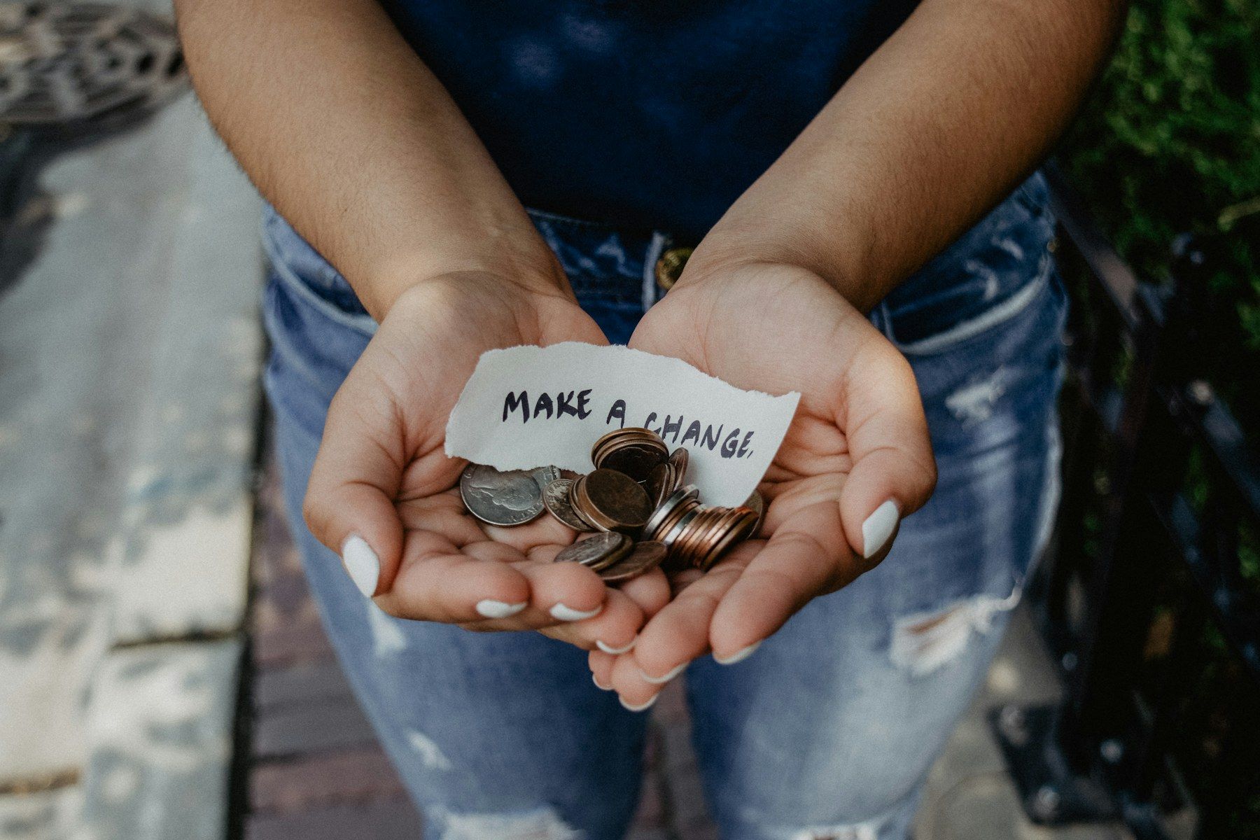 Cupped hands holding coins and a note that reads “make a change”