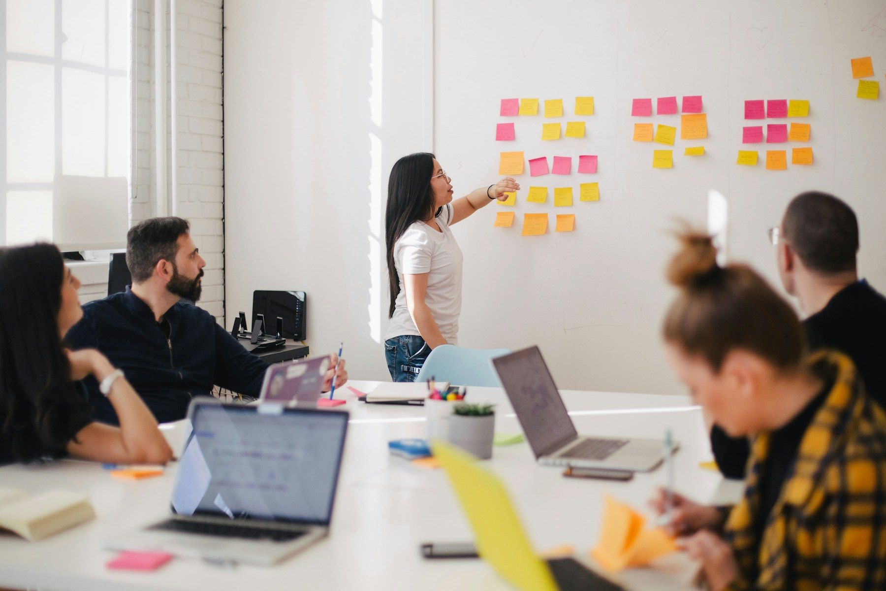 A colleague presenting ideas on a wall of sticky notes to her team