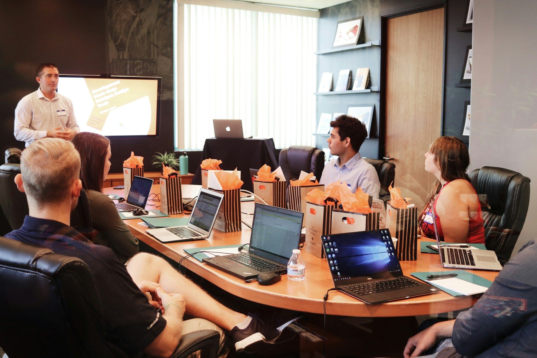 A team meeting around a conference table while a colleague presents