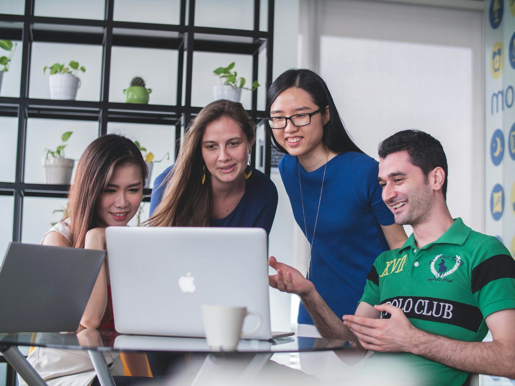 A start-up team gathered around a laptop, smiling