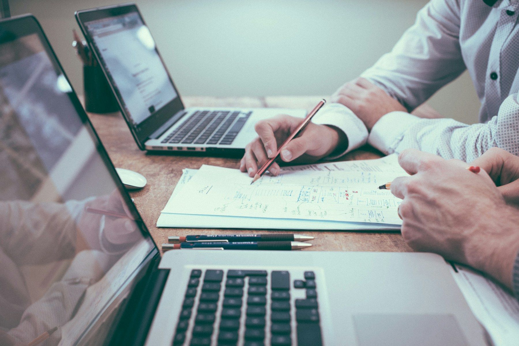 An adviser annotating financial papers beside a laptop