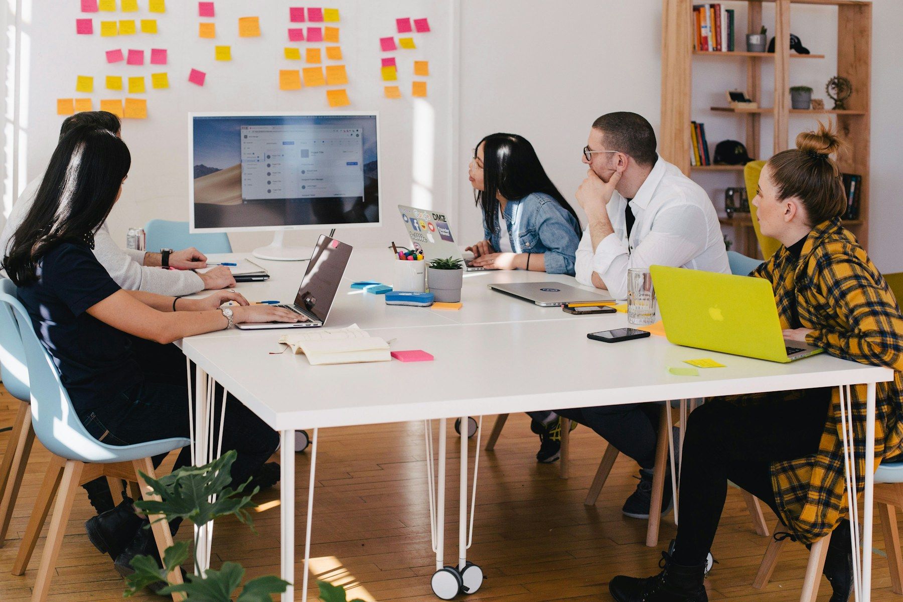 A team planning together around a table with laptops and sticky notes